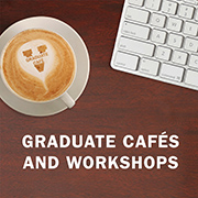 A cup of coffee with 'Graduate Café' written on the foam, next to a computer keyboard on a wooden surface. Text above reads 'GRADUATE CAFÉS AND WORKSHOPS'.