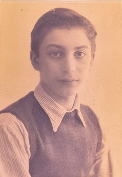 Black and white posed portrait of young man in sweater vest and button-up shirt. He looks earnestly at the camera.